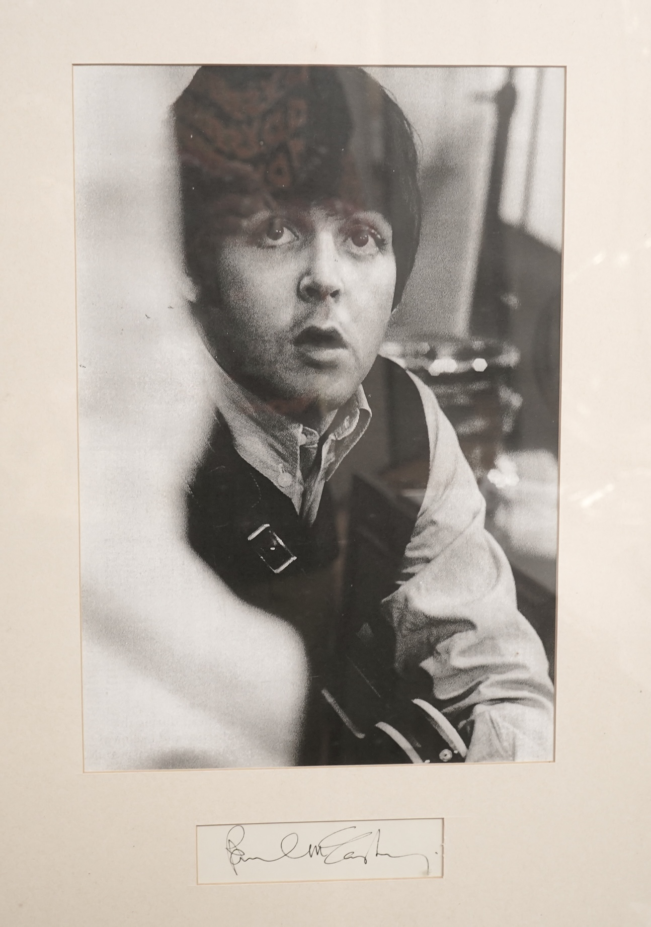 A framed autograph of Paul McCartney, signed in black ink, mounted below a black-and-white photograph of McCartney taken from a 1960s image, dimensions of frame; 66 x 48cm